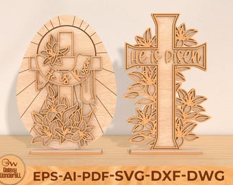 May include: Two wooden laser cut Easter decorations. One is a cross with the words "He is Risen" and the other is an egg with a cross and the words "He is Risen". Both decorations are surrounded by floral designs.