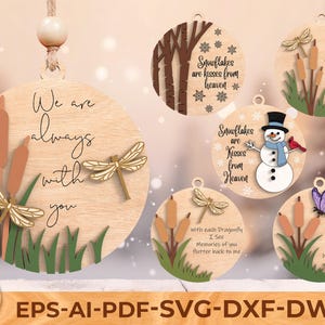 Op de afbeelding: Houten ronde ornamenten met natuurthema's. Eén heeft libellen en de tekst "We are always with you." Een andere toont een sneeuwpop en de tekst "Snowflakes are kisses from Heaven." Andere ontwerpen omvatten lisdodden en vlinders.