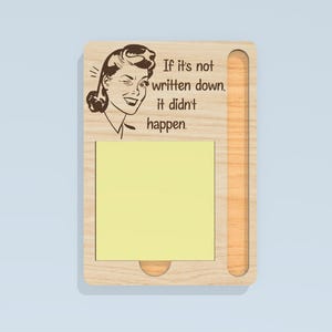 May include: Wooden memo board with a retro illustration of a woman and the text "If it's not written down, it didn't happen." The board has a slot for a notepad and a small, round cutout at the bottom.
