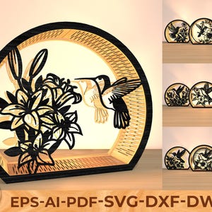 May include: A wooden, laser-cut hummingbird and lily flower scene within a circular frame. The design is black and natural wood, with the hummingbird in flight. The image includes the text "Galaxy Wonderall" and file type options.