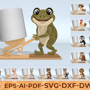 Könnte beinhalten: Ein Toilettenpapierhalter aus Holz mit einer grünen und braunen Froschfigur, die einen Halter im Schubkarrenstil mit einer weißen Papierrolle hält. Weitere Tierdesigns sind ebenfalls abgebildet.
