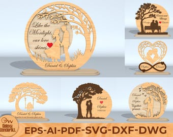 Puede incluir: Diseños de madera cortados con láser con temas románticos. Los diseños incluyen parejas, árboles y corazones. El texto incluye nombres y frases como "Like the Moonlight, our love shines" y "Forever".