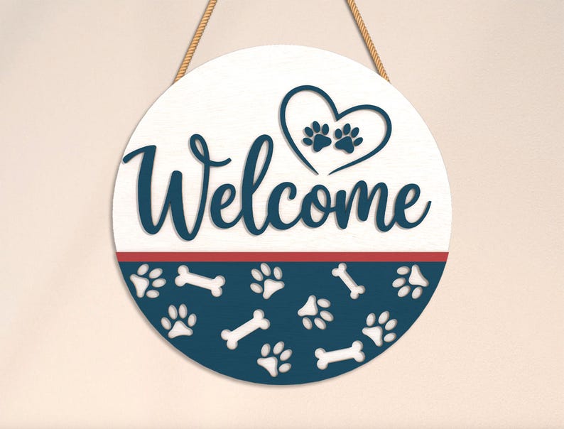 May include: A round wooden sign with the word "Welcome" in navy blue script. The top half is white, with a heart and paw prints. The bottom half is navy blue with paw prints and bone shapes. A red stripe separates the two halves.