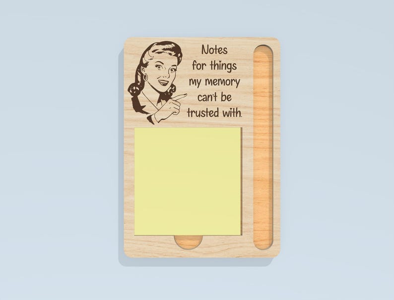 May include: Wooden memo board with a retro illustration of a woman pointing, and the text "Notes for things my memory can't be trusted with." Includes a yellow sticky note pad and a slot for a pen or pencil.