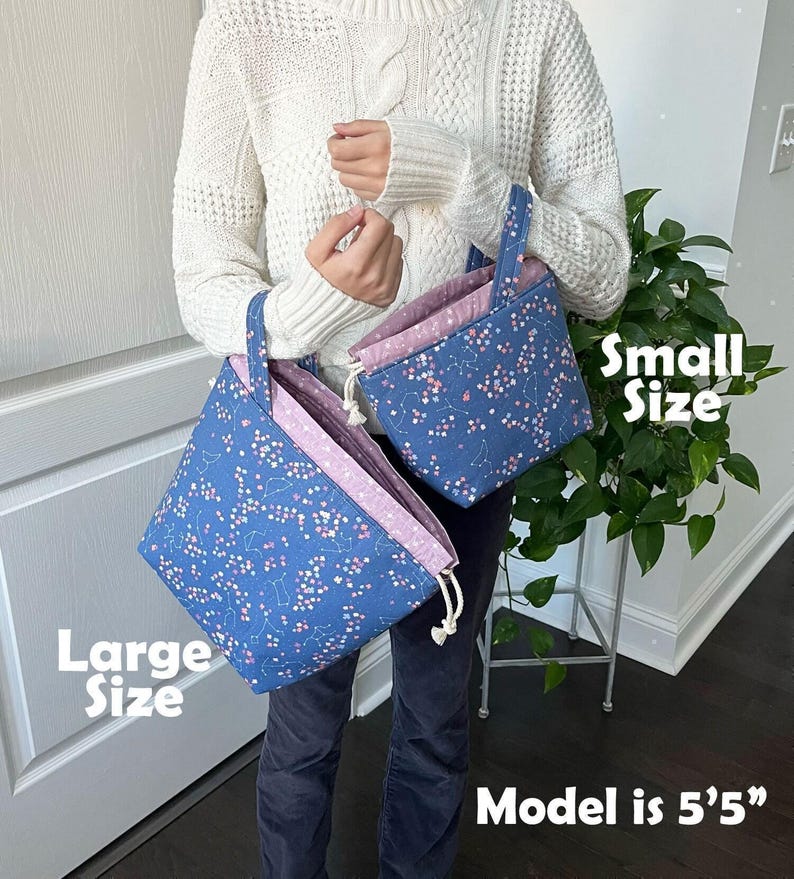 A person is holding two bags, one large and one small, with a plant in the background.