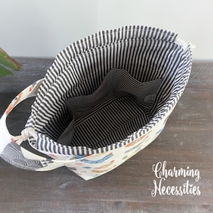 an open tote bag with a striped interior, resting on a wooden surface.