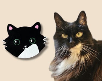 Könnte beinhalten: Eine schwarz-weiße Katzendarstellung mit großen grünen Augen, rosa Innenohren und einem weißen Fleck am Kinn, neben einer langhaarigen schwarz-weißen Katze mit grünen Augen und einem weißen Fleck auf der Brust.