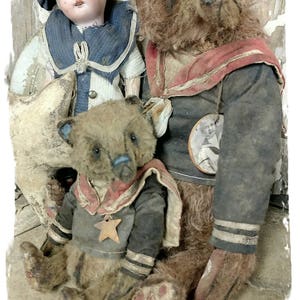 以下が含まれることがあります： 水兵服を着たテディベア2体。1体は赤と白のストライプの襟と黒と白のストライプの袖が付いた茶色のベア。もう1体は青と白のストライプの襟と黒と白のストライプの袖が付いた茶色のベア。両方のベアは胸に星が付いています。青と白の水兵服を着た磁器製のドールがベアたちの後ろに座っています。