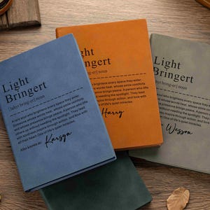 Puede incluir: Cuatro cuadernos rectangulares en azul, naranja, gris y verde oscuro. Cada portada presenta el texto impreso Light Bringert, una definición estilo diccionario y un nombre personalizado en letra cursiva sobre una superficie de madera.