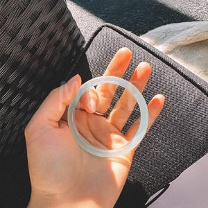 K&ouml;nnte beinhalten: Ein hellgr&uuml;nes Jade-Armband. Das Armband ist glatt und poliert.