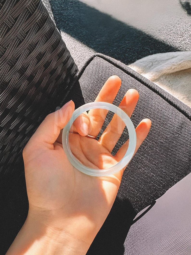 K&ouml;nnte beinhalten: Ein hellgr&uuml;nes Jade-Armband. Das Armband ist glatt und poliert.