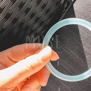 K&ouml;nnte beinhalten: Ein hellblauer Silikonring, der in einer Hand gehalten wird.