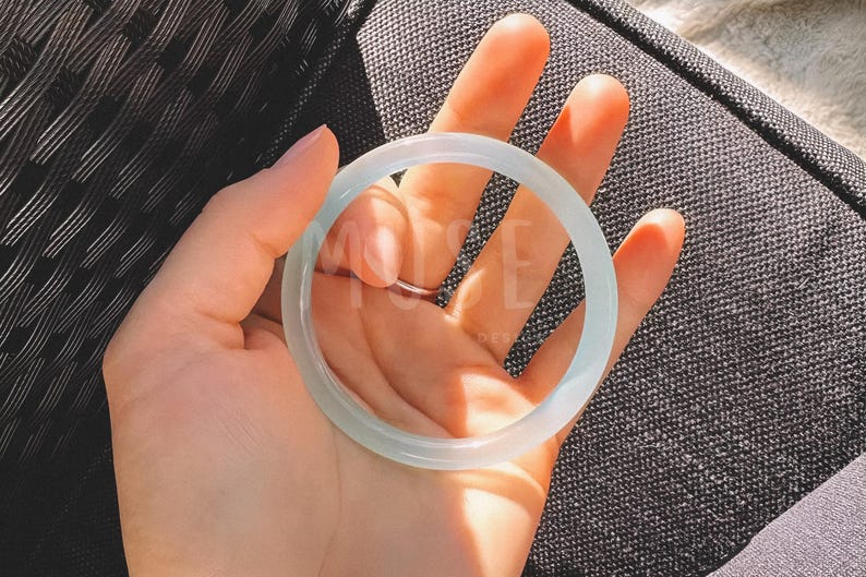 K&ouml;nnte beinhalten: Ein wei&szlig;es Jade-Armband. Das Armband ist glatt und poliert und hat eine leicht durchscheinende Optik.