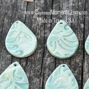 May include: Ten teal blue ceramic teardrop-shaped pendants with a white floral design.  www.CapturedMoments.Etsy.com Made in Texas, USA