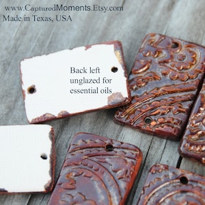 May include: Close-up of ceramic tiles with a brown glaze and intricate patterns. The back left tile is unglazed, with the text "Back left unglazed for essential oils".