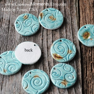 May include: A set of seven ceramic round ornaments with a turquoise blue glaze and a swirl pattern. The ornaments have a hole at the top for hanging. The back of one ornament is white and says "back".