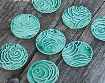 May include: Eight teal blue ceramic ornaments with a swirl design. Each ornament has a hole at the top for hanging.