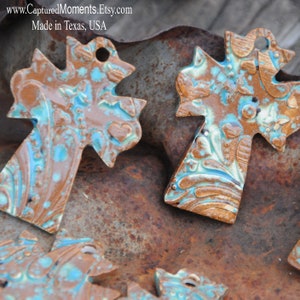 May include: Four ceramic cross ornaments with a turquoise and brown glaze. The crosses have a detailed floral pattern and are made in Texas, USA.