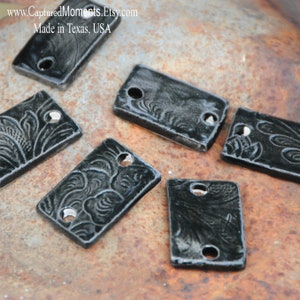 May include: Six black ceramic rectangular tags with a decorative design and two holes. The tags are on a rusty metal surface. www.CapturedMoments.Etsy.com Made in Texas, USA