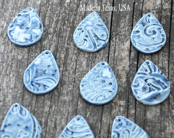May include: Ten blue ceramic teardrop-shaped pendants with various white and blue patterns. The pendants have a hole at the top for hanging.