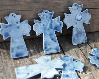 May include: Several blue ceramic crosses with a marbled effect and small holes for hanging. The crosses have a glossy finish and are arranged on a weathered wooden surface. The text "CapturedMoments.Etsy.com" and "Made in Texas, USA" are visible.