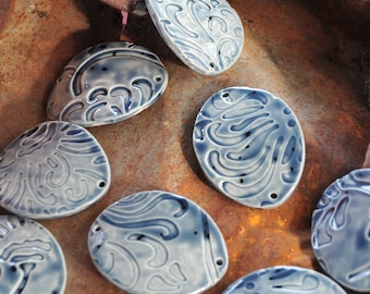 May include: A collection of eight ceramic tiles with a blue and white swirl design. The tiles are arranged in a semi-circle on a rusty metal surface.