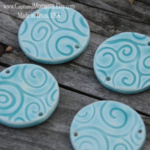 May include: Four turquoise blue ceramic round ornaments with a swirl pattern. Each ornament has a hole for hanging.