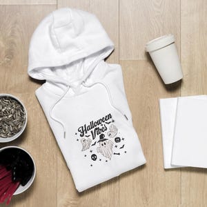 Op de afbeelding: Witte hoodie met een zwart-witte grafische print met de tekst "Halloween Vibes" met een spook en vleermuizen.