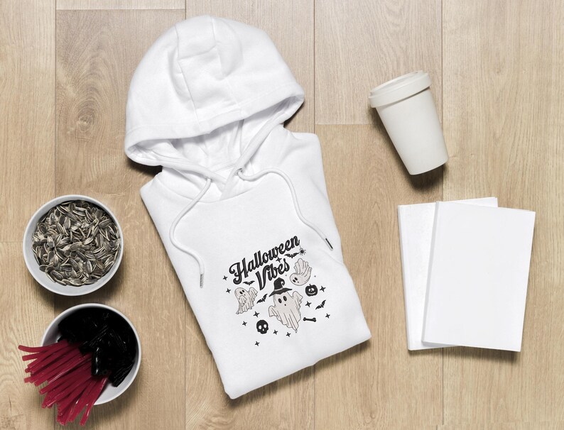 Op de afbeelding: Witte hoodie met een zwart-witte grafische print met de tekst "Halloween Vibes" met een spook en vleermuizen.