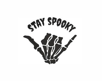 May include: Black and white graphic design of a skeleton hand giving the shaka sign with the text "STAY SPOOKY" above it.