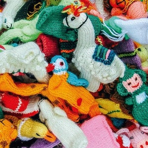 Puede incluir: Un surtido colorido de juguetes tejidos a mano, incluyendo llamas, monos y pájaros. Los juguetes son de varios colores como blanco, verde, naranja y amarillo. La imagen es una toma de cerca de los juguetes.