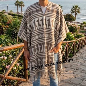 May include: A beige and brown patterned poncho with fringe, featuring a geometric design and llama figures. The poncho is worn with blue jeans and brown boots. The image includes the text "incastreasures.com".