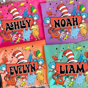 May include: Four colorful t-shirts with custom names and Dr. Seuss-inspired graphics. Each shirt features a different name: Ashley, Noah, Evelyn, and Liam. The designs include the Cat in the Hat's hat, characters, and stars.