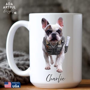 May include: A white ceramic mug featuring a graphic of a French Bulldog wearing a grey utility vest filled with tools and a rolled blueprint. The dog is positioned above the name Charlie written in black script. The text ADA ARTFUL DELIGHTS is visible.