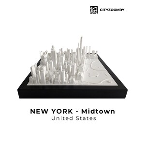 Op de afbeelding: Een wit 3D-model van Midtown Manhattan, New York City, op een zwarte basis. Het model bevat gedetailleerde weergaven van wolkenkrabbers en Central Park. De tekst "NEW YORK - Midtown United States" staat eronder.