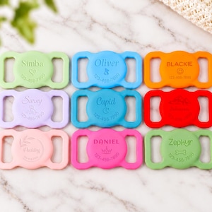 Op de afbeelding: Negen siliconen identificatielabels voor huisdieren in diverse kleuren zoals lichtgroen, blauw, oranje, paars, teal, rood en roze. Elk label heeft een centraal gedeelte met een naam, een klein icoontje en het telefoonnummer 123-456-7890.