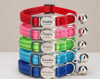May include: A stack of five nylon pet collars in red, pink, green, light blue, and dark blue. Each collar features a reflective strip, a grey plastic buckle, a silver metal ID tag with a name and phone number, and a small silver bell.