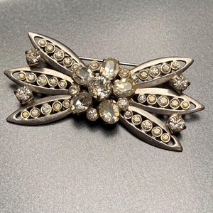 Vintage, unusual 1940s rhodium plated silver tone and sparkly clear glass rhinestones, flower / bow design brooch with rollover clasp