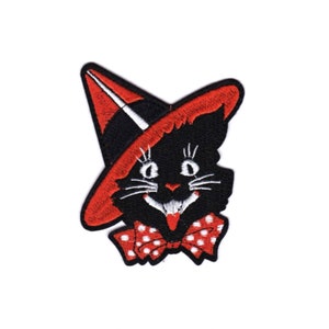 May include: Embroidered patch featuring a black cat wearing a witch hat with a red brim and a red bow tie with white polka dots. The patch measures approximately 4 inches by 3.75 inches. The cat has a smiling expression and white whiskers. A Halloween-themed item.