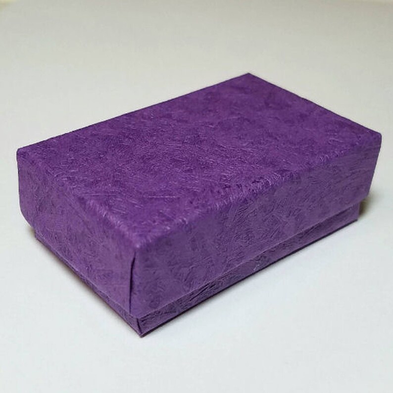 May include: A small, purple gift box with a textured paper finish. The box is ideal for holding small items like jewelry or other trinkets.
