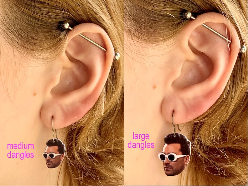 Pode incluir: Dois pares de brincos com o rosto de uma pessoa. Os brincos &agrave; esquerda s&atilde;o etiquetados como "medium dangles" e os brincos &agrave; direita s&atilde;o etiquetados como "large dangles".