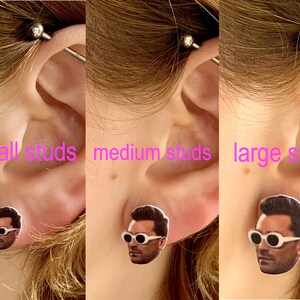 May include: Three images showing different sizes of earrings featuring a man's face with white sunglasses. The text "small studs", "medium studs", and "large studs" is written below each image.