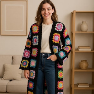 May include: A long, black crochet cardigan with vibrant floral squares. The cardigan is worn over a white top and blue jeans. The garment has long sleeves and a knee-length hemline, ideal for layering, and is approximately 100 cm in length.