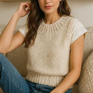 Peut inclure: Un gilet en tricot crème avec un col détaillé et un ourlet côtelé. Le gilet est porté sur un t-shirt blanc et associé à un jean bleu. L'esthétique générale est décontractée et confortable, adaptée au quotidien.