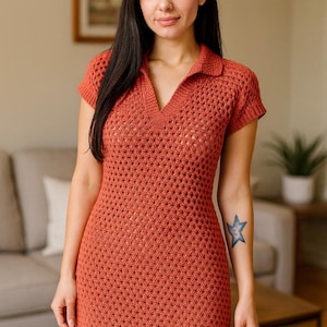 May include: A rust-colored, short-sleeved crochet dress with a collared neckline and a V-neck. The dress has a fitted silhouette and a textured, open-weave design. The model is wearing the dress.