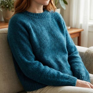 May include: A teal knitted sweater with a crew neck and long sleeves. The sweater has a textured appearance and a relaxed fit. The garment is made of a soft, warm material, suitable for cooler weather. The sweater is a versatile item of clothing.