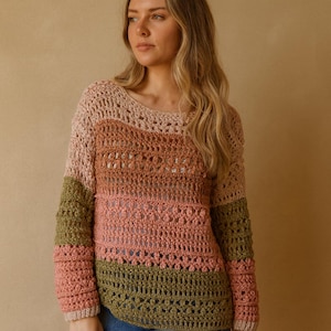 Pode incluir: Um suéter de crochê com design de blocos de cores. O suéter apresenta decote redondo e mangas compridas. Os blocos de cores incluem tons de rosa, verde oliva e bege. O ponto de crochê cria uma textura aberta e arejada.