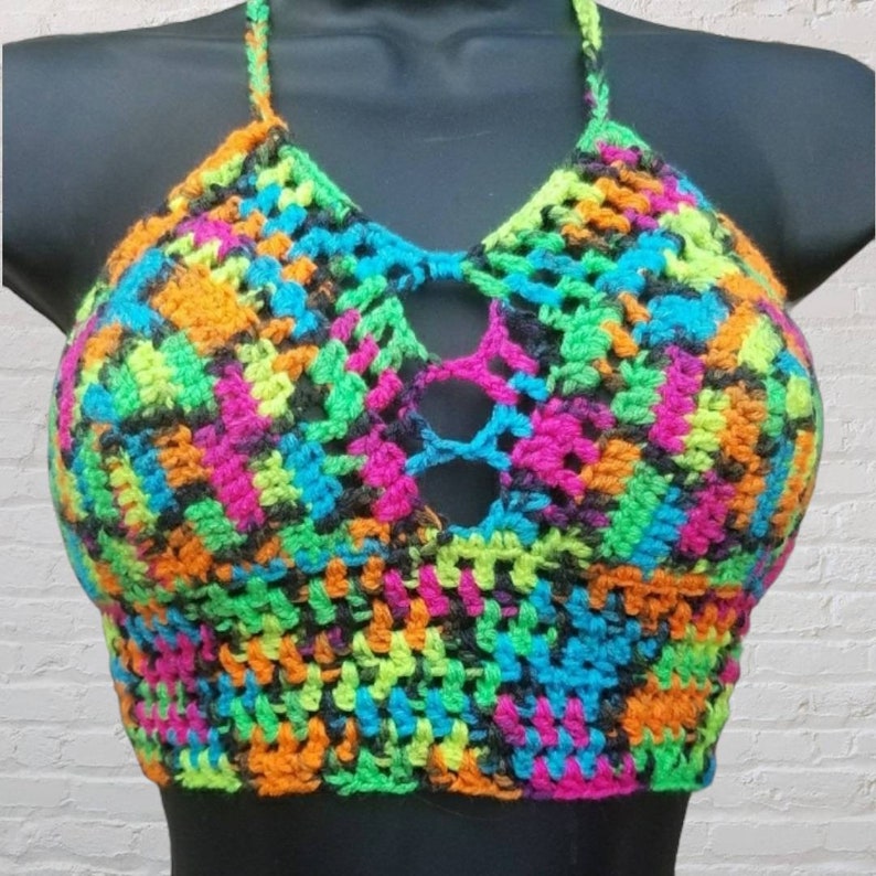 May include: A colorful crochet halter top with a geometric pattern in shades of pink, orange, green, blue, and black.