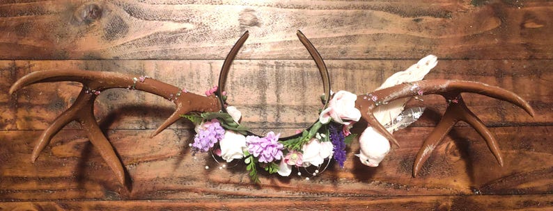 May include: A headband with a brown antler design and a floral garland with white and purple flowers.
