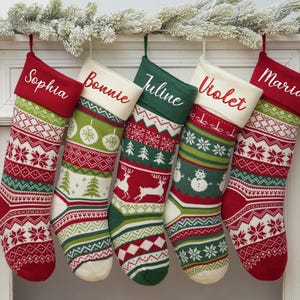 May include: Five red and green Christmas stockings with white trim and different patterns. The stockings are personalized with the names Sophia, Bonnie, Juline, Violet, and Maria.
